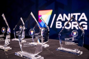 Clear acrylic diamond shaped awards in front of a wall with the AnitaB.org logo